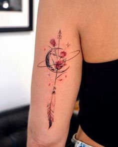 a woman's arm with an arrow and rose tattoo on the back of her shoulder