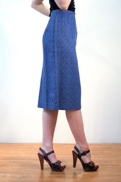 "This is a classic vintage 1960s blue paisley print pencil skirt. It features vertical pleats below the waistband, a center walking vent in the back, and a hem that ends just below the knee. It has a stylized, subtle floral paisley pattern, in turquoise green and navy blue on a deep blue background. The fabric is a sturdy cotton with a satin lining inside at the waist. The skirt closes with a button at the left hip and a 6 inch metal side zipper that is expertly placed, so that it is completely Retro Fitted Knee-length Skirt, Retro Blue Lined Skirt Bottoms, Retro Fitted Knee-length Pencil Skirt, Vintage Fitted Midi Skirt, Vintage Fitted Knee-length Pencil Skirt, Fitted Vintage Blue Skirt, Vintage Blue Skirt For Work, Retro Fitted Midi Skirt, Retro Fitted Lined Pencil Skirt