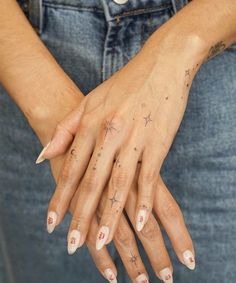 a woman's hands with tattoos on them and her nails in the shape of stars