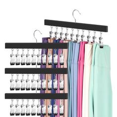 an assortment of pants hanging from hooks on a rack in front of a white background