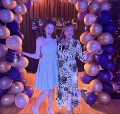 two women are standing in front of balloons