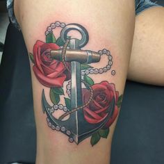 an anchor and roses tattoo on the thigh