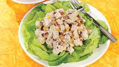 a plate with lettuce and chicken salad on it next to a bowl of dressing