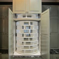 an open refrigerator in a kitchen filled with lots of white containers and cupboards on the wall