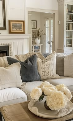 a living room filled with lots of furniture and flowers on top of a coffee table