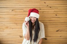 a woman wearing a red and white hat while talking on a cell phone in front of a wooden wall