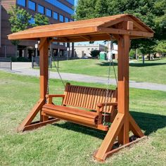 a wooden swing in the grass near a building