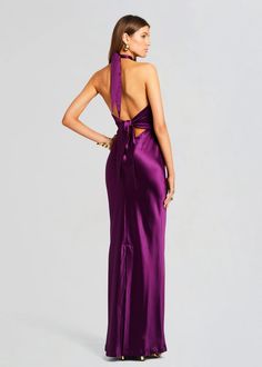 a woman in a purple dress with her back turned to the camera and looking down