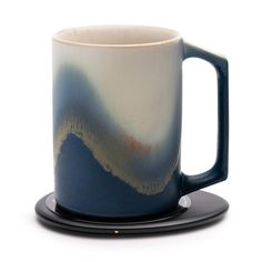 a blue and white coffee mug on a black saucer with a plate underneath it