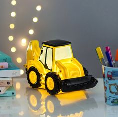 a yellow toy bulldozer sitting on top of a table next to some books