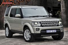 a silver land rover is parked in front of a building with an orange sign above it