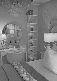 black and white photograph of a bedroom with chandelier, bed, desk and mirror