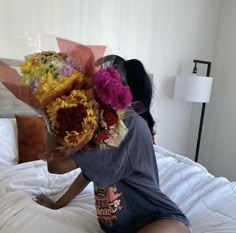 a woman sitting on a bed holding flowers