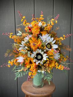 a vase filled with lots of flowers sitting on top of a wooden table next to a wall