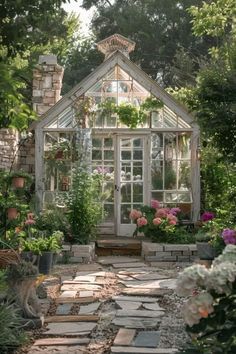 an old greenhouse is surrounded by flowers and greenery