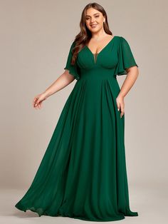 a woman in a green dress posing for the camera with her hands on her hips