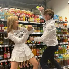 a man and woman dancing in front of a store display filled with bottles of juice