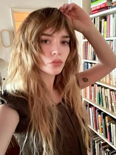 a woman standing in front of a bookshelf with her hand on her head