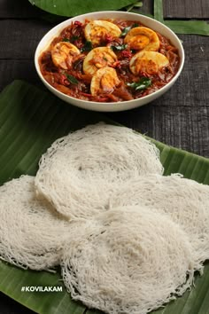 some noodles are in a white bowl on a green plate next to another dish with shrimp