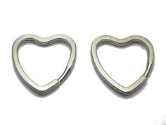 two metal heart shaped objects on a white surface