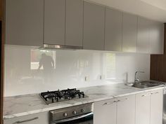 a kitchen with white cabinets and marble counter tops