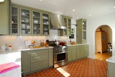 a kitchen with green cabinets and an orange tile floor is shown in the foreground