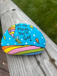 a painted rock that says on the places you'll go sitting on a wooden bench