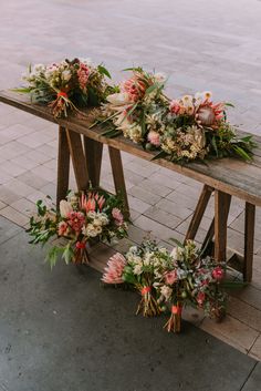 two wooden benches with flowers and greenery on them