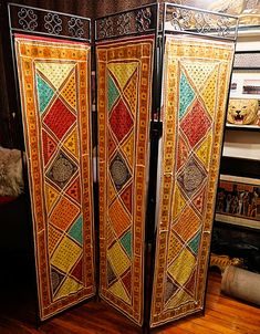 a room divider with an intricate design on the top and bottom panel, sitting in front of a wooden floor