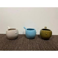 three ceramic pots sitting on top of a carpeted floor