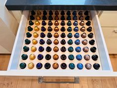 an open drawer with several different colored glass knobs on the bottom and one in the middle