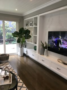 a living room filled with furniture and a flat screen tv mounted on a wall next to a window