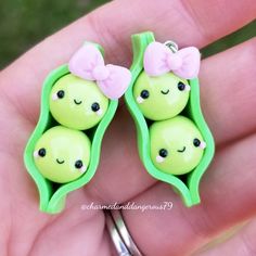 two peas are sitting in the shape of pea pods with a pink bow on their head