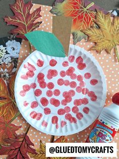 a paper plate that has been made to look like an apple with leaves on it