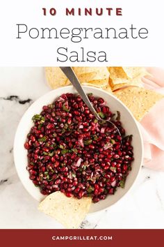 pomegranate salsa in a white bowl with tortilla chips on the side