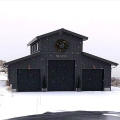 a black building with a wreath on the front and two garages in the back