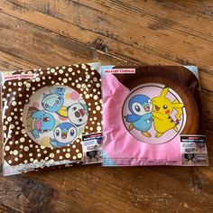 two plates with pokemon designs on them sitting on a wooden floor