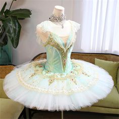 a ballerina dress sitting on top of a table in front of a couch and potted plant