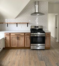 an empty kitchen with wooden cabinets and stainless steel stove top oven in the center of the room