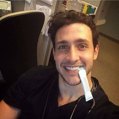 a man is smiling and brushing his teeth with an electric toothbrush in his mouth