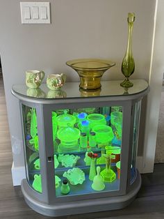 there is a display case with green glass items on the top and bottom shelves in front of it