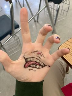 a person's hand with a tattoo on it that has an open mouth and tongue