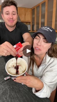 a man and woman sitting at a kitchen table with food in front of their faces