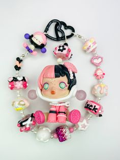 a doll with lots of charms around it on a white surface and in the background is a keychain