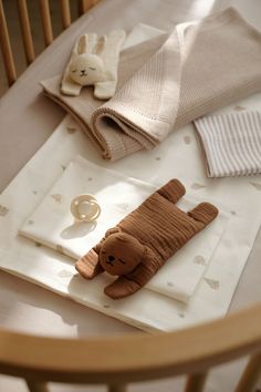 a teddy bear is laying on the table next to some folded towels and napkins