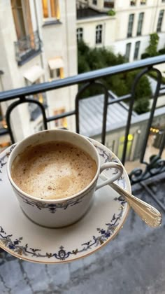 a cup of coffee sitting on top of a saucer next to a balcony railing