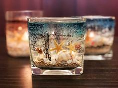 three glass jars filled with sand and starfish on top of a wooden table next to each other