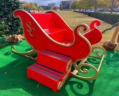 a red and gold sleigh sitting on top of green grass