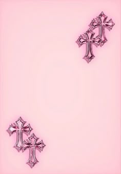 two shiny metal crosses on a pink background