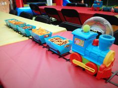 a toy train sitting on top of a table next to some bowls filled with food